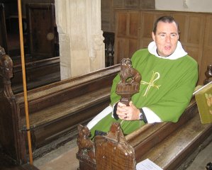 Revd Ian Finn seated in one of the pews missing its finial Finials